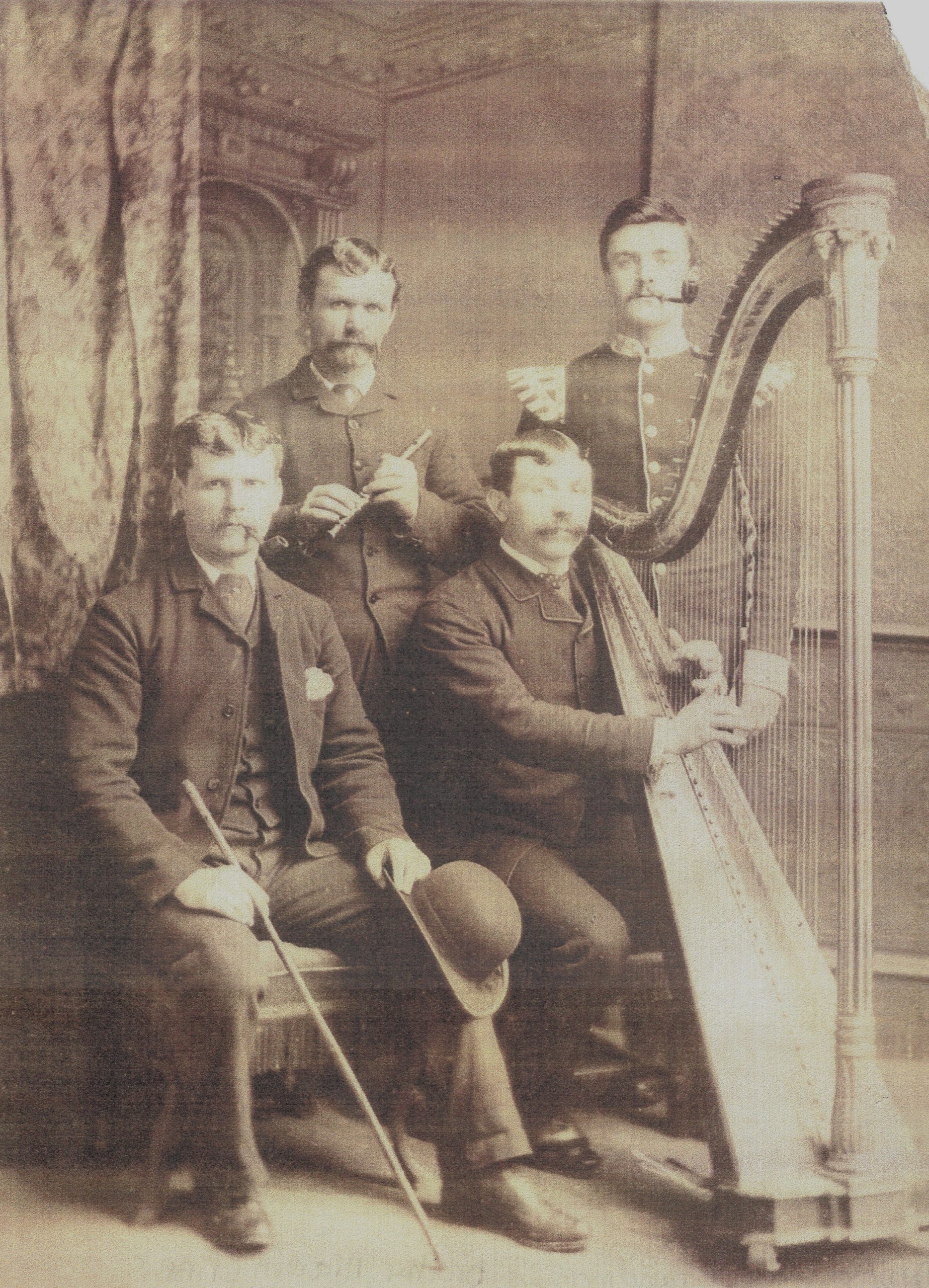 A picture of Aladdin Senior seated playing the harp with 3 other musicians around hi,