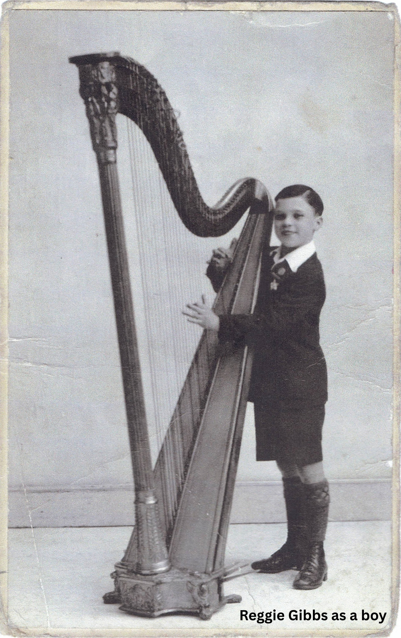 A photograph of Reggie Gibbs as a child standing playing his harp