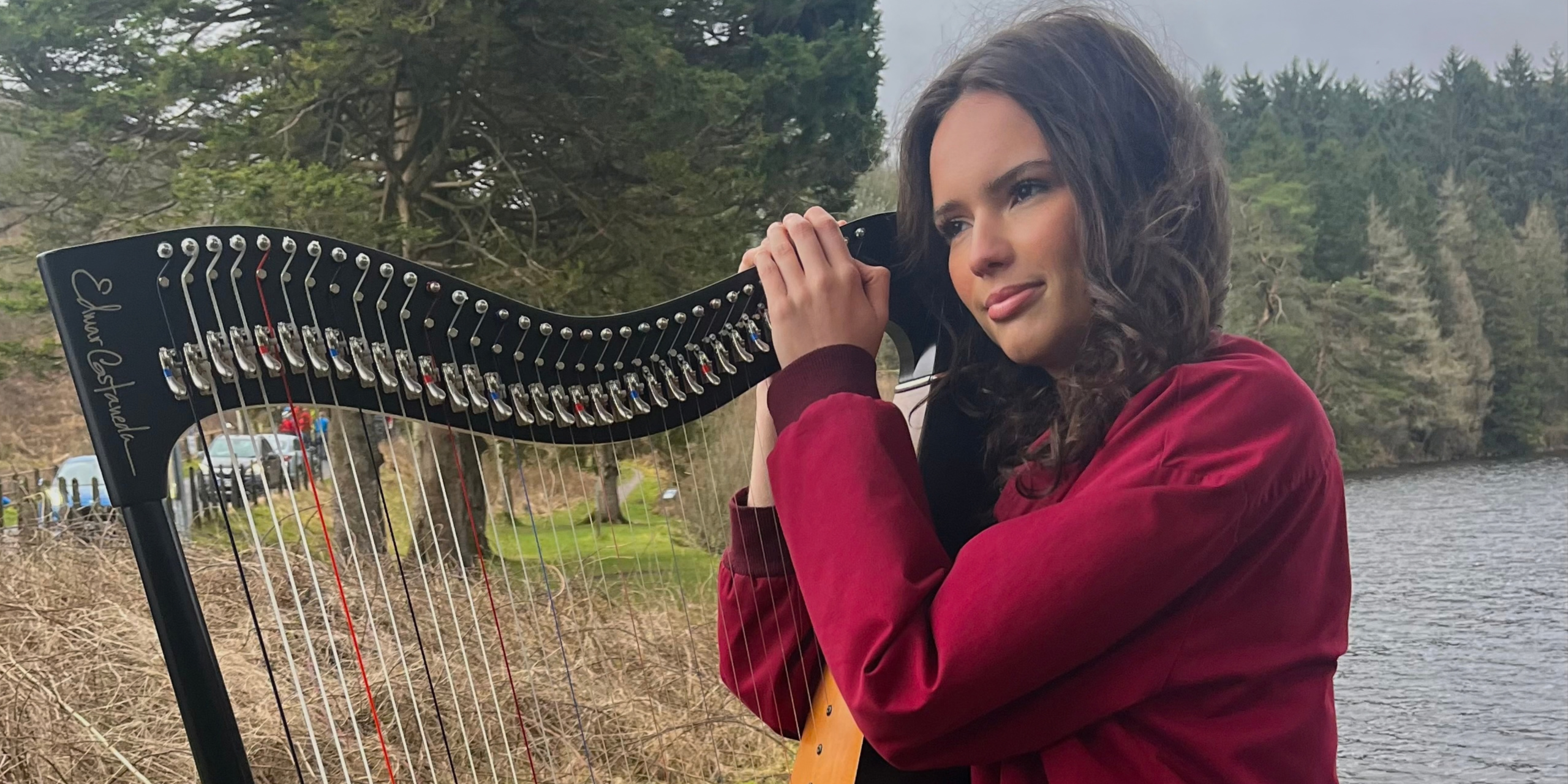 This is a photograph of Arwen standing with her harp next to Ponsticill Reservoir